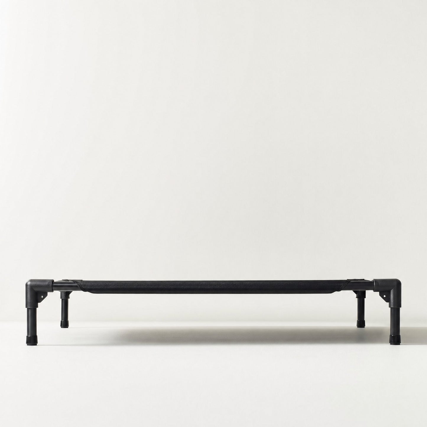 The cot seen at floor level, the gap underneath reading as a band