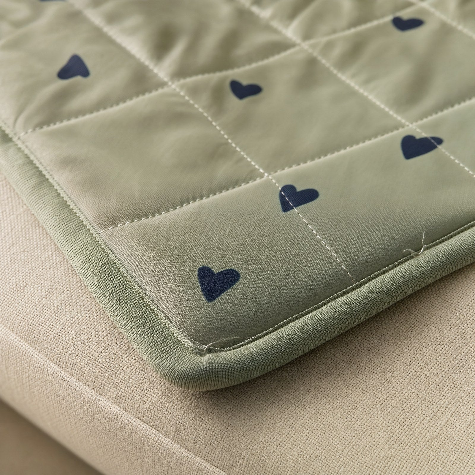 Close-up of the quilted sage green fabric and its bound edge