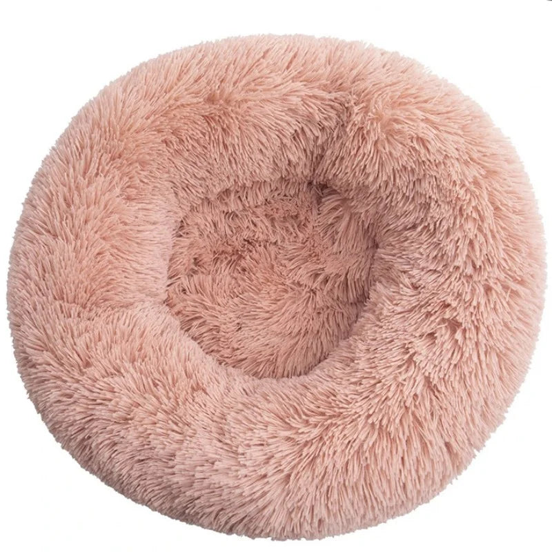 A dusty pink warming plush donut dog bed