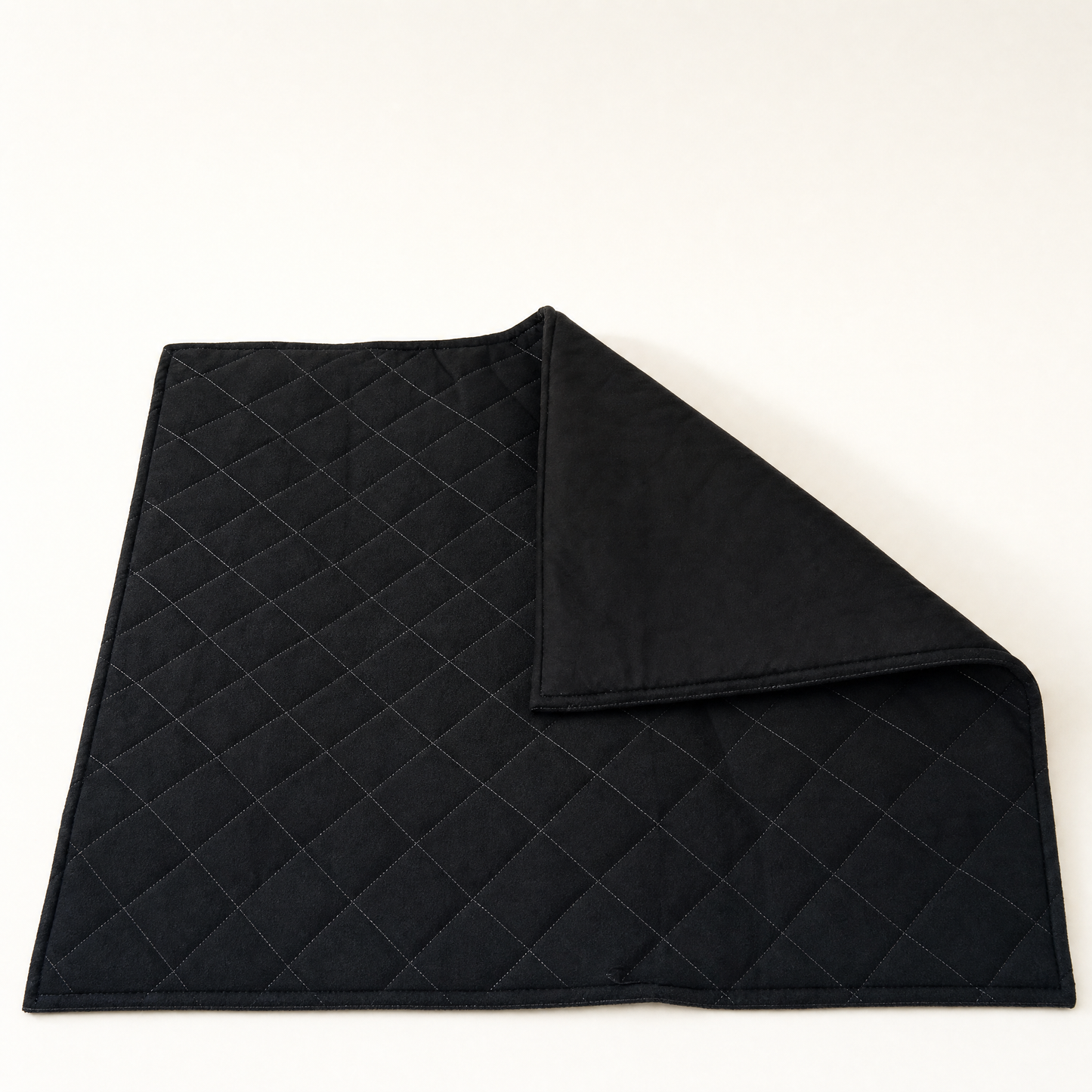 One corner folded back to show the plain black underside beside the quilted face